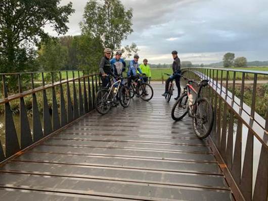 A group of people riding bikes on a bridge

Description automatically generated