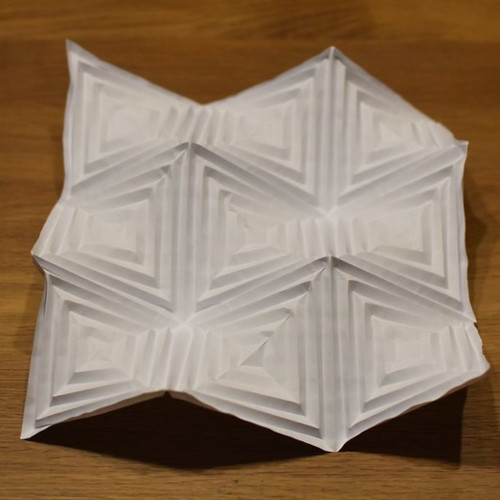A white folded paper on a wood surface

Description automatically generated